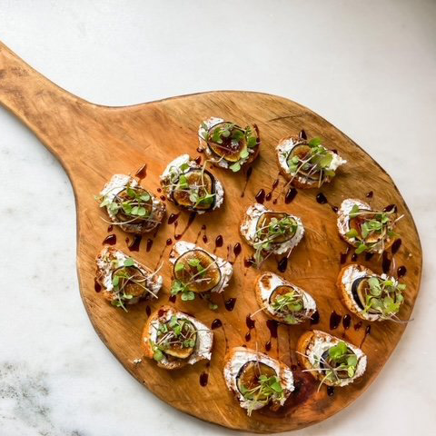 image of an assortment of hors d'oeuvres drizzled with balsamic sitting upon a wood serving board