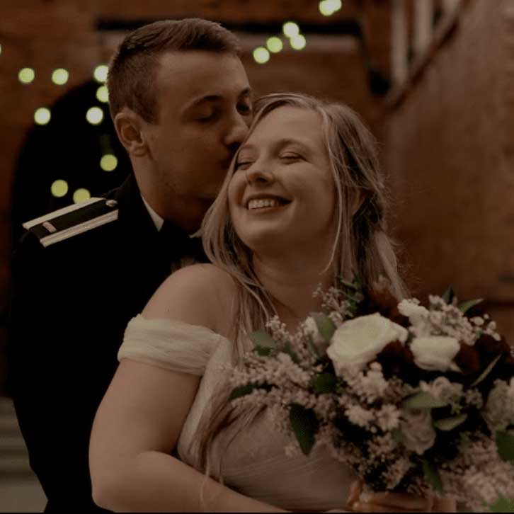 Image of groom holding his bride and kissing her head in a very loving and warm gesture.